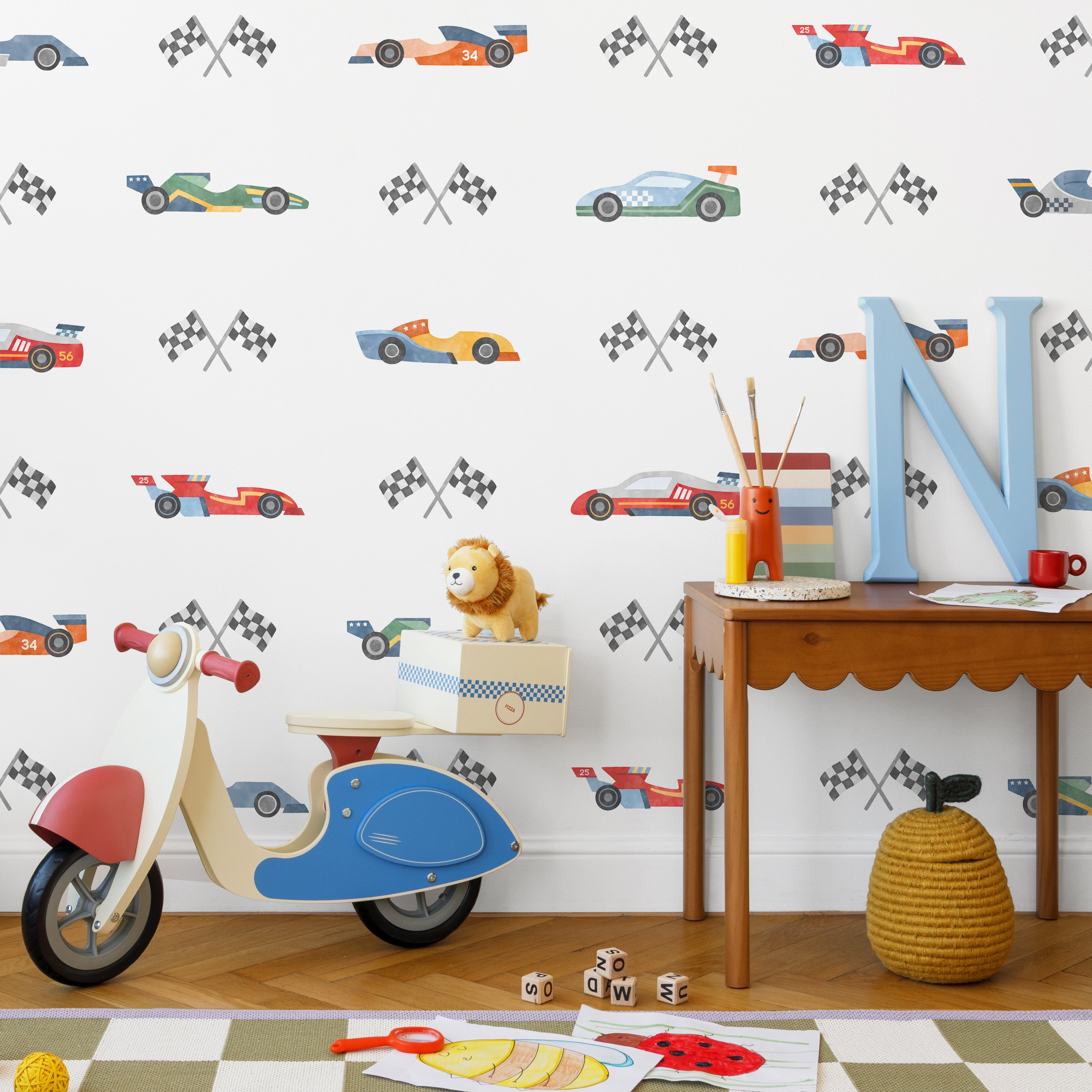 Children's room with race car themed wallpaper featuring various colorful race car decals, along with children's toys and furniture.